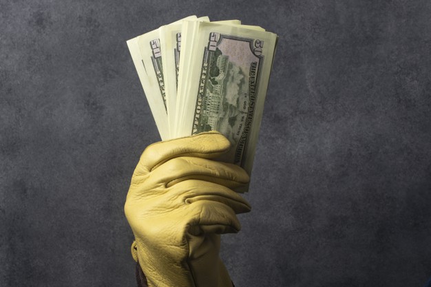gloved hand holding a wad of dollars 275805 120